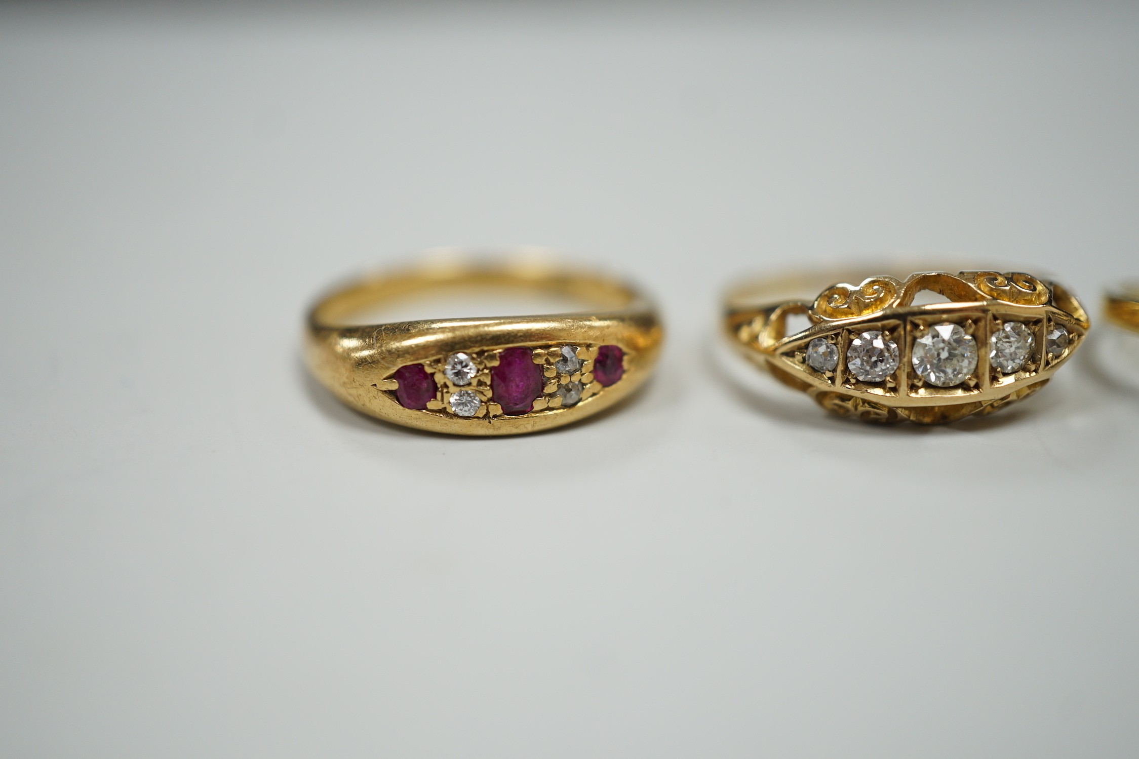 Three early 20th century 18ct and gem set rings, including ruby and diamond chip, size O, graduated five stone diamond, size P and an emerald and diamond cluster, size M, gross weight 10 grams.